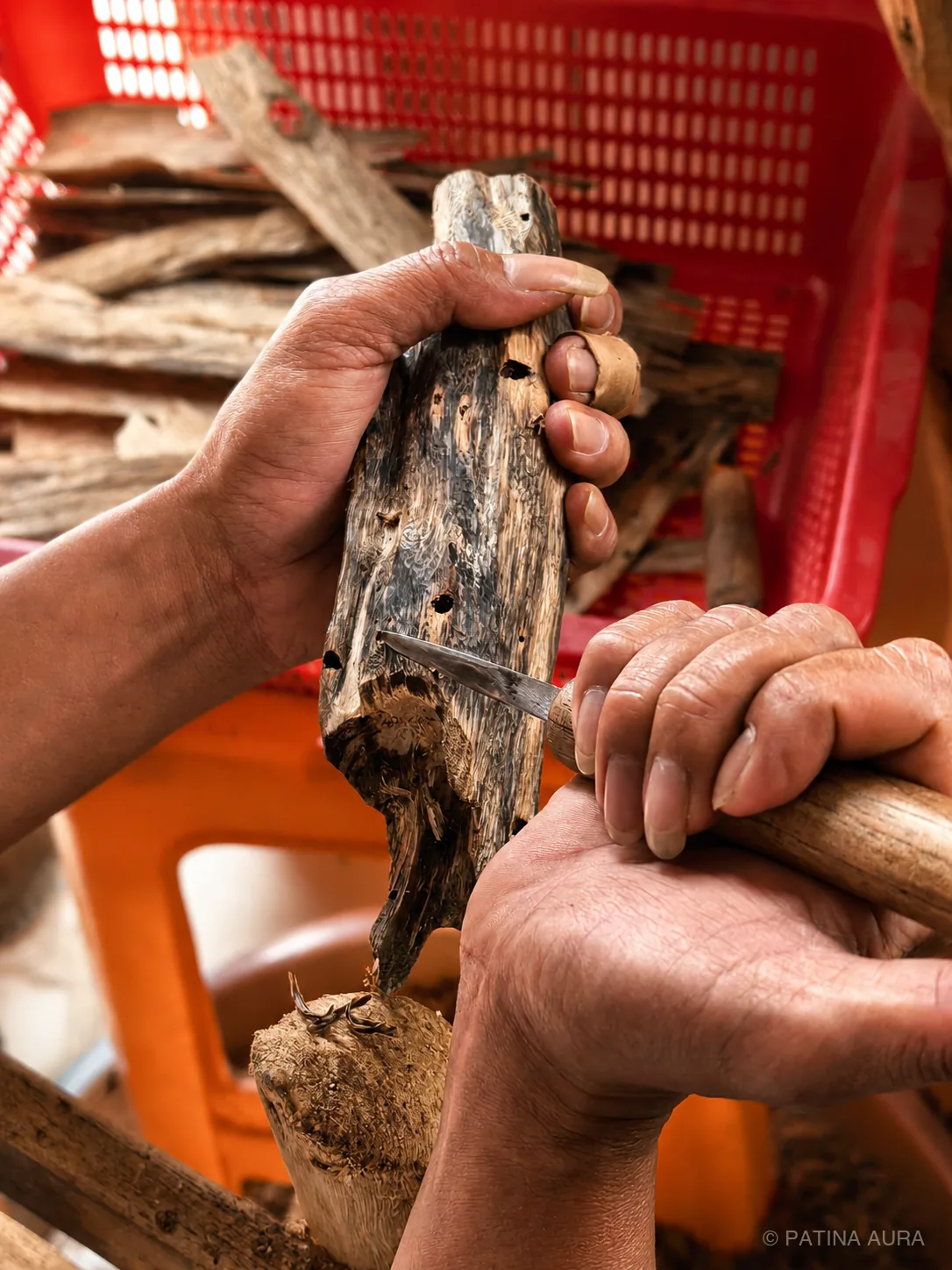 Artisan carefully scraping and examining a piece of kynam agarwood by hand